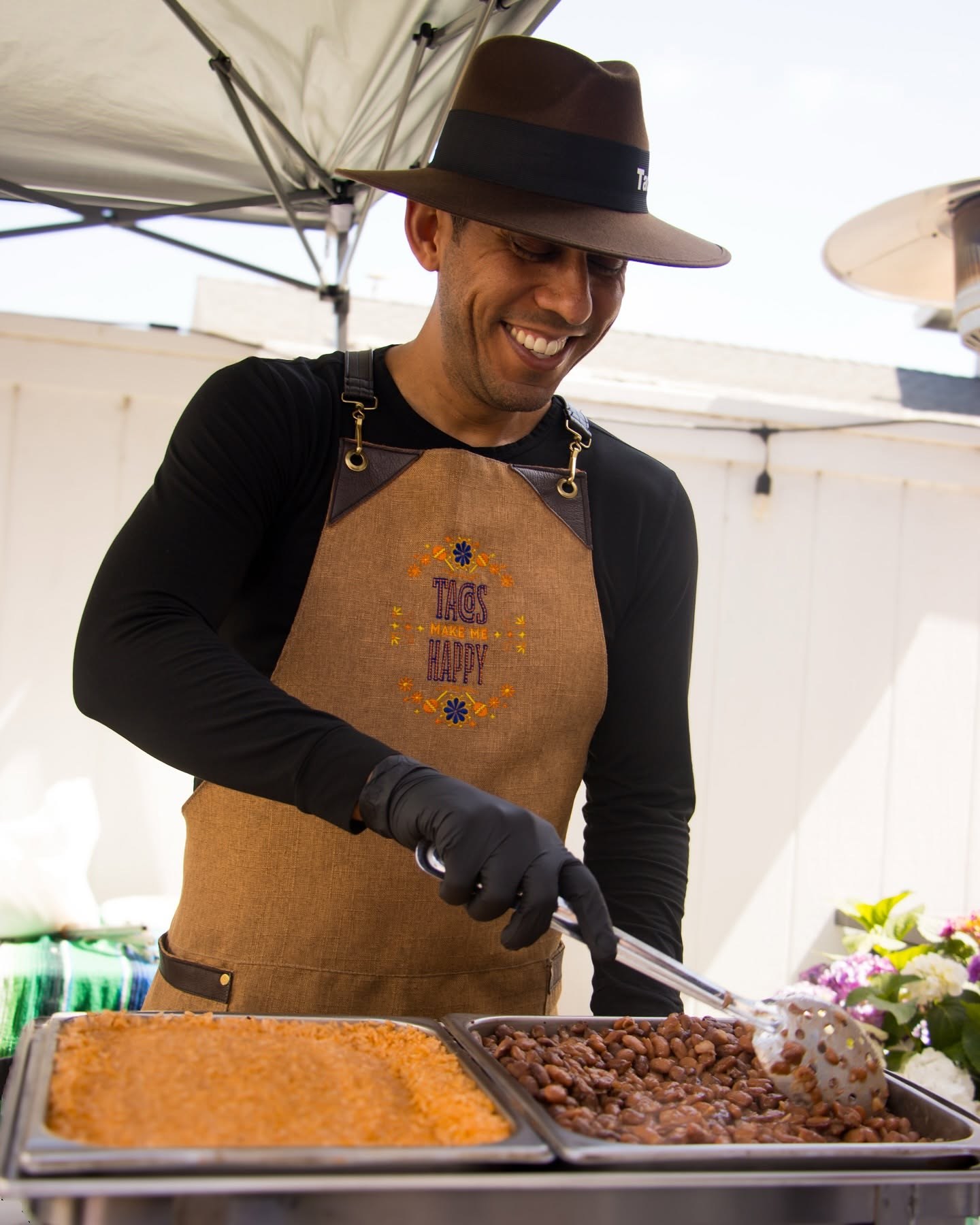 Ángel serving rice and beans at a Tacos Don Jorge catering station