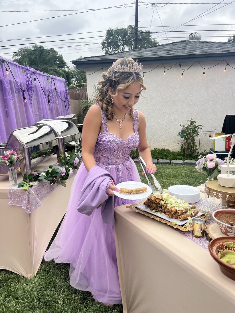 Quinceañera in a lavender gown serving herself from the Tacos Don Jorge taco buffet