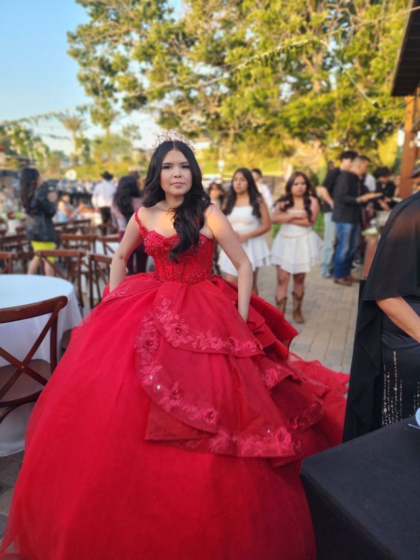 Quinceañera in a red ballgown at her outdoor celebration
