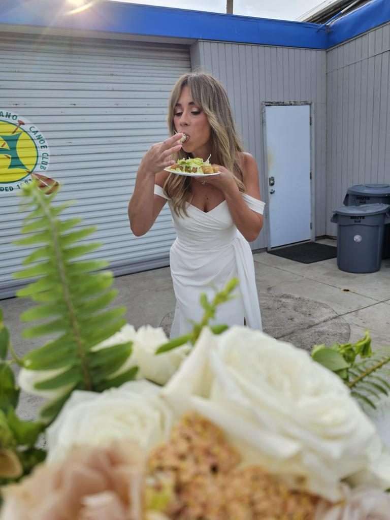Bride enjoying a taco plate surrounded by white roses