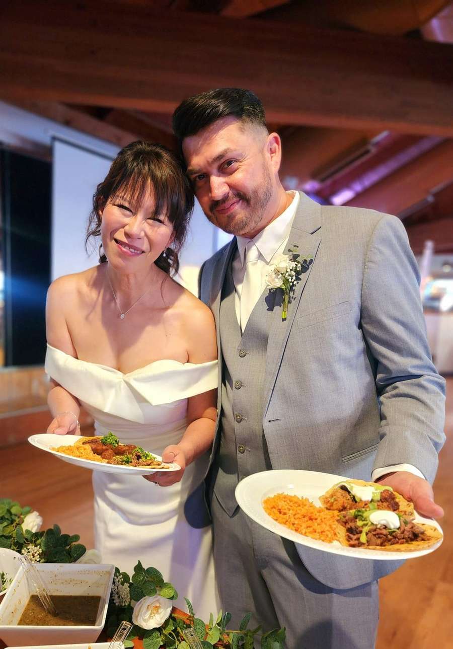 Newlyweds holding taco plates at their banquet hall reception