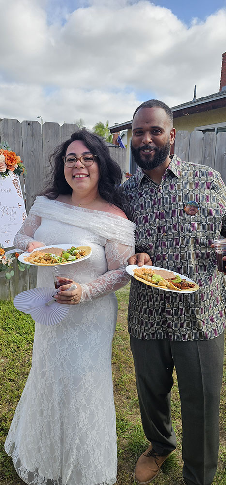 Newlyweds embracing while holding a plate of Tacos Don Jorge wedding catering